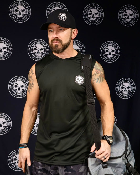 A man wearing a black sleeveless hooded t-shirt with a logo on the chest, standing in front of a backdrop with multiple logos.