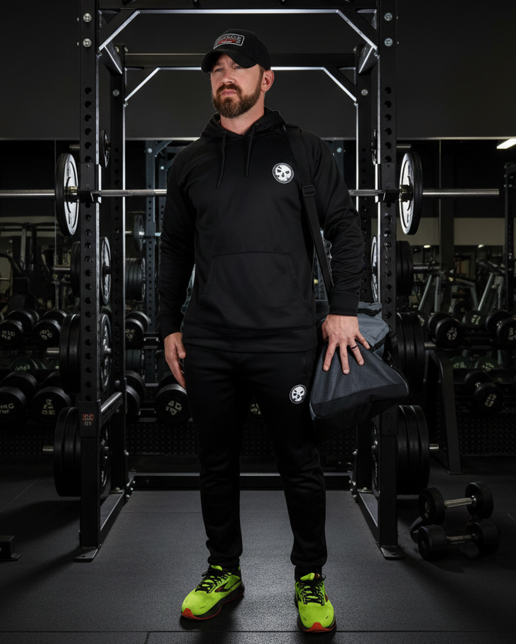Man wearing the Black Unisex Performance Hooded Sweatshirt with gym bag