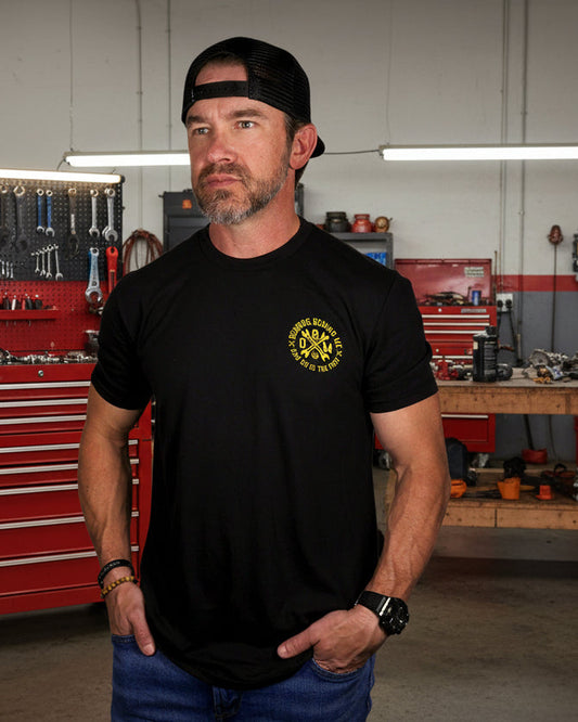 Man wearing a black t-shirt with a yellow logo and a black cap on a white background