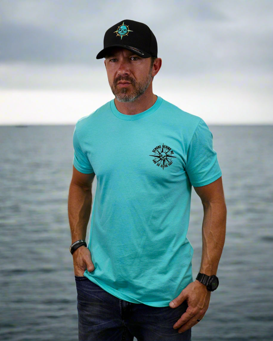 Man wearing a turquoise t-shirt with a black logo and a black cap on a white background