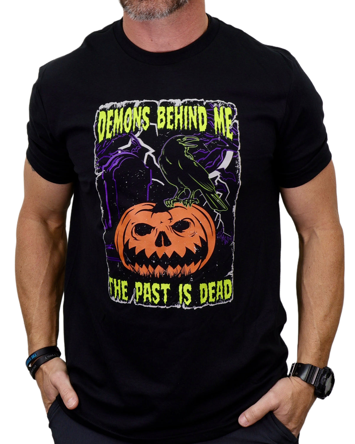 Black t-shirt with Halloween-themed design featuring a pumpkin and text, worn by a person.