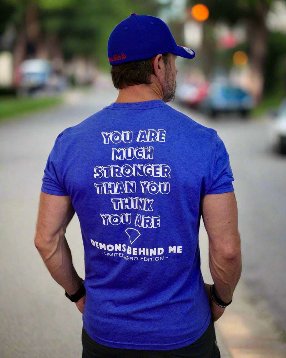 Man wearing a blue t-shirt with motivational quote on the back, standing against a white background