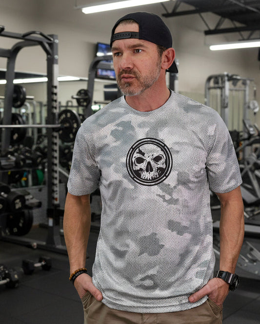 Man wearing a gray camouflage t-shirt with a black and white logo on a white background