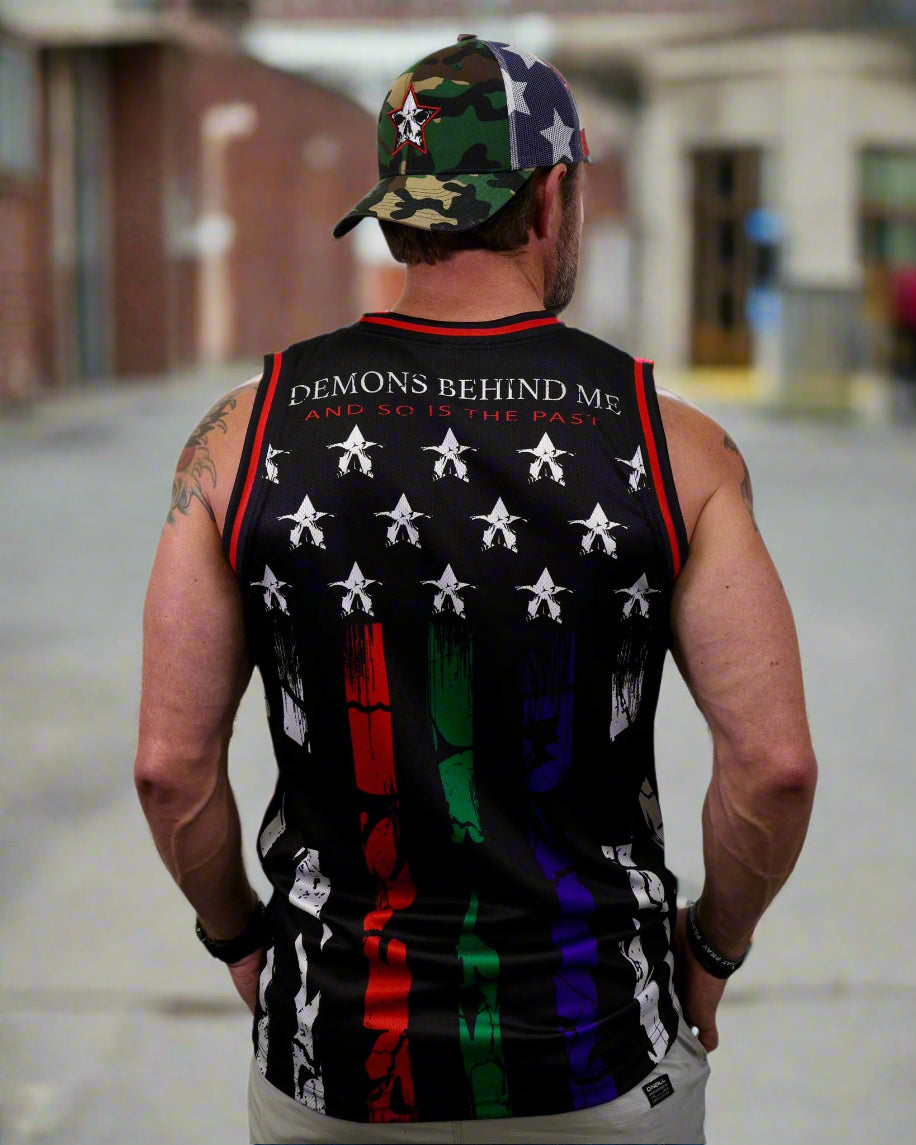 Person wearing a sleeveless shirt with a colorful design and text on the back, standing against a white background.