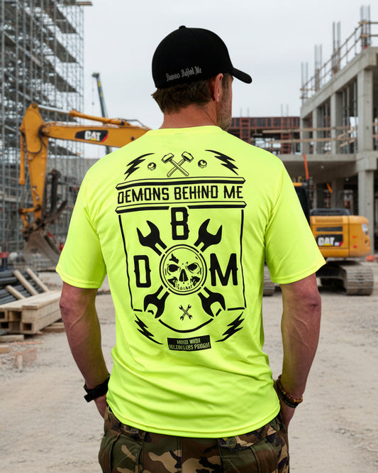 Person wearing a bright yellow t-shirt with black graphics and text on the back, standing against a white background.