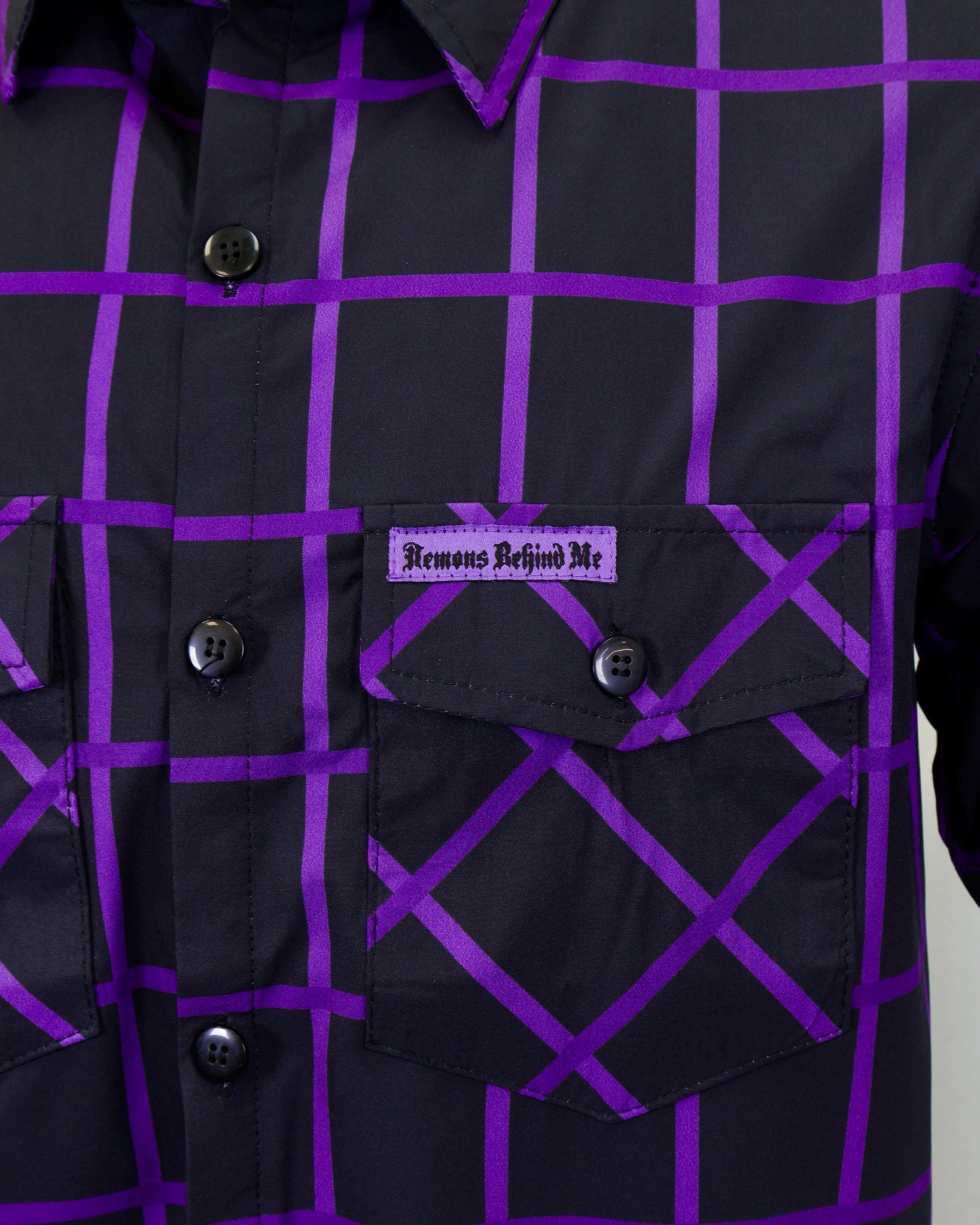 Black shirt with purple grid pattern and brand label on a gray background