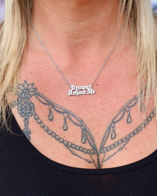 Necklace with a pendant worn by a person with tattoos on their neck.